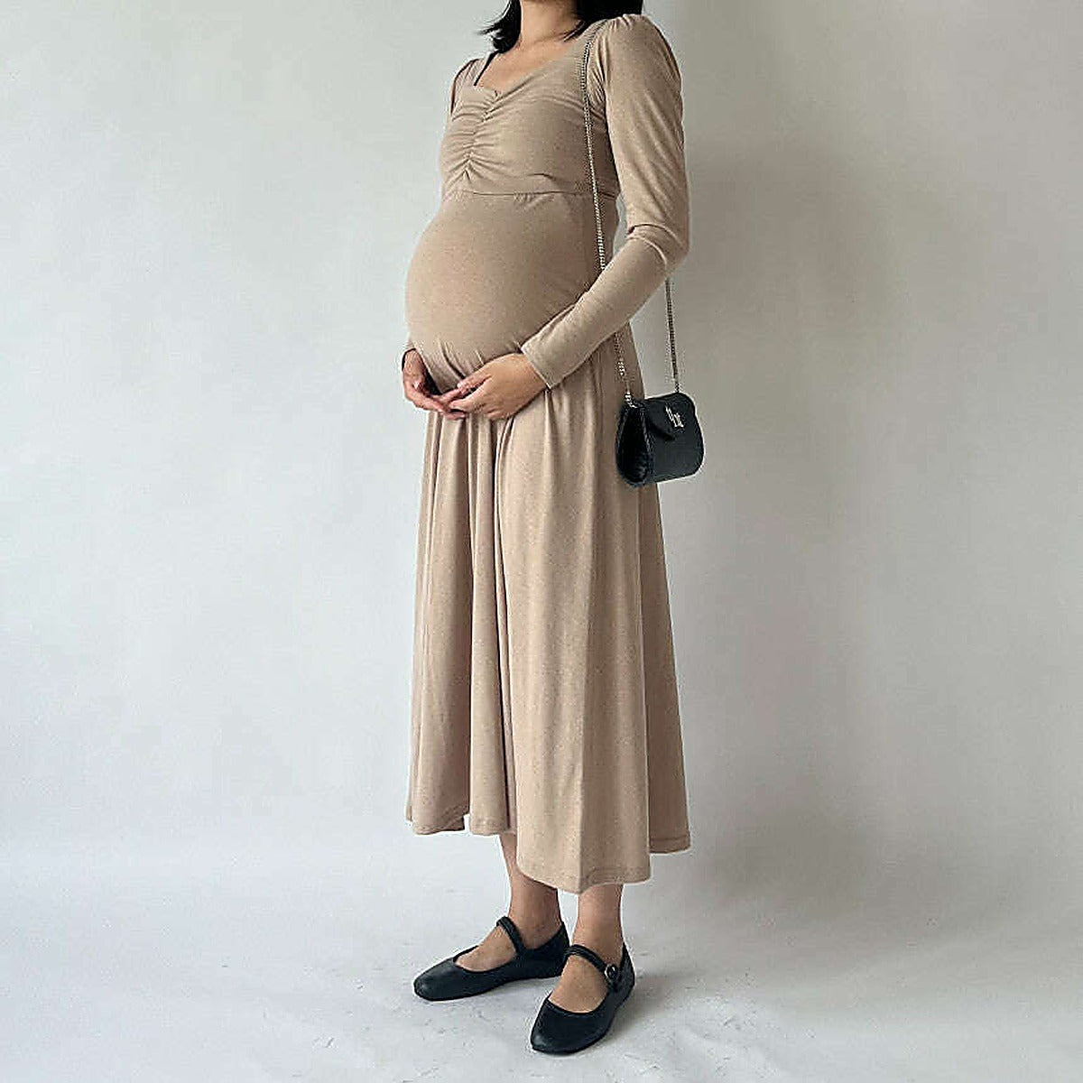 模特兒實穿米色連身裙，站於鏡前手扶孕肚｜孕婦心領抽褶舒適連身長裙（第 1 張）