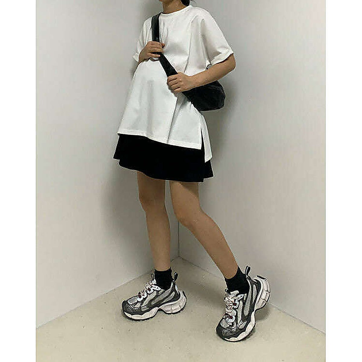 模特兒實穿白色 T 恤配黑色短褲，站於鏡前｜反袖A字寬鬆前短後長上衣（第 7 張）