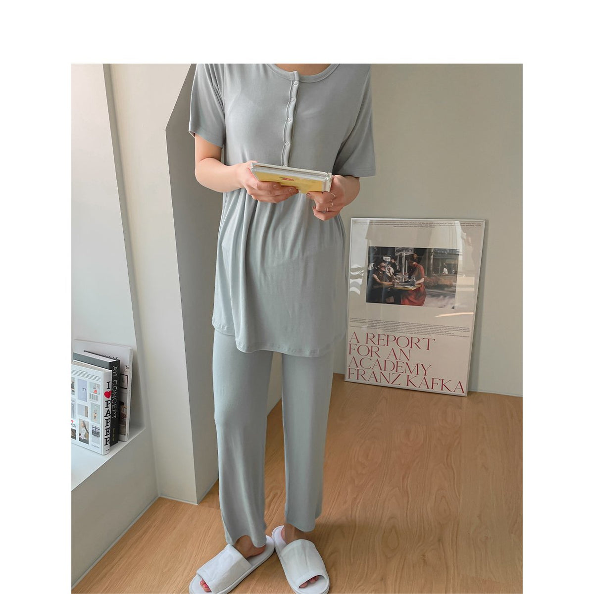 灰藍色短袖連身裙，圓領前排鈕扣，模特正面站立手握書本，淺色居家背景｜孕婦短袖鈕扣柔軟人造絲哺乳套裝（第 211 張）